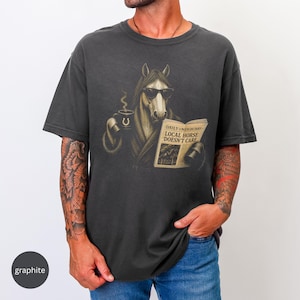 Vintage engraved horse wearing sunglasses and a robe while reading a newspaper and holding a steaming coffee mug. Humorous horse lover design featuring the headline “Local Horse Doesn't Care” in an antique newspaper style. Detailed equestrian artwork with a relaxed, unbothered attitude.