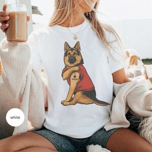 German Shepherd dog illustration wearing a red shirt, lifting sleeve to reveal “I love mom” tattoo, vintage style retro pet graphic, bold clean lines, centered composition, perfect for dog lovers and animal themed apparel designs
