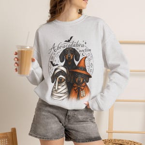 Dachshund Halloween long sleeve and sweatshirt design with three black and tan dogs, mummy wraps, orange witch hat, bats and spell symbols.