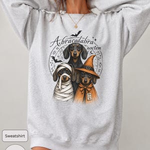 Dachshund Halloween long sleeve and sweatshirt design with three black and tan dogs, mummy wraps, orange witch hat, bats and spell symbols.