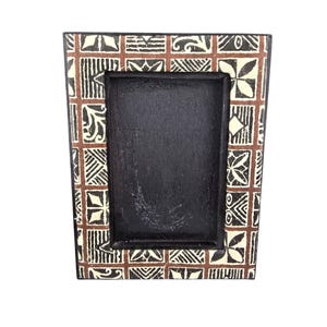 May include: Black wooden picture frame with a patterned border. The border has a repeating design of brown, cream, and black geometric shapes. The frame has a dark interior space for a photo.