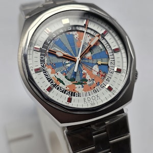 Op de afbeelding: Een roestvrijstalen Edox Geoscope horloge met een witte wijzerplaat met een wereldkaartontwerp in blauw, oranje en groen. Het horloge heeft een zilveren band en een datumweergave.
