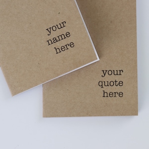 May include: Two brown kraft paper notebooks with white edges. The top notebook has the text "your name here" printed on the cover. The bottom notebook has the text "your quote here" printed on the cover.