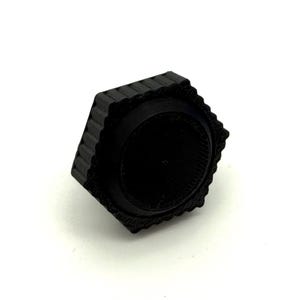 以下が含まれることがあります： 黒色の六角形のオブジェクトで、外側の縁に溝があり、内側は円形です。 オブジェクトは、固体でマットな素材でできており、白い背景に配置されているようです。