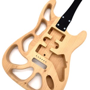 May include: An unfinished electric guitar body made of light-colored wood with a hollowed-out, skeletal design. It features a black neck plate attached with four screws, multiple routed cavities for electronics, and a bridge mounting area.