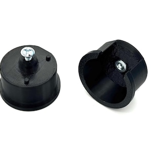 May include: Two black, 3D-printed objects on a white background. One is a cylindrical base with a screw, and the other is a curved, open-ended piece with a screw. Both appear to be components of a larger item.