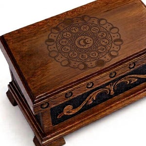 May include: A rectangular wooden box with a dark brown finish, featuring a laser-engraved circular mandala design on the lid that includes zodiac symbols and moon phases. The front panel displays a carved wooden scrollwork pattern over a black background.
