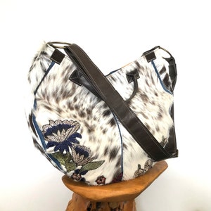 Round hair-on cowhide bag with embroidered flowers, top handles and adjustable crossbody or shoulder strap