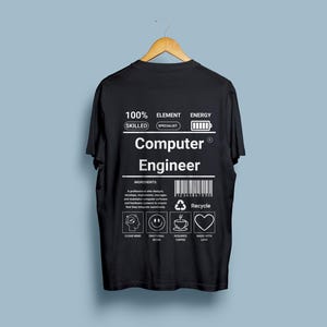 May include: Black t-shirt with a white graphic design that says "100% Skilled Element Specialist Energy Computer Engineer". The graphic also includes a battery icon, a barcode, and a recycle symbol.