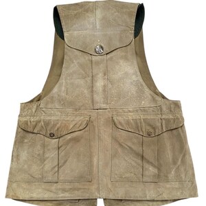 Peut inclure: Un gilet de couleur beige avec plusieurs poches et une fermeture &agrave; bouton. Le gilet a un col haut et un aspect vieilli, sugg&eacute;rant qu'il est fait d'un mat&eacute;riau durable. Il comporte deux grandes poches sur le devant et une plus petite sur la poitrine.