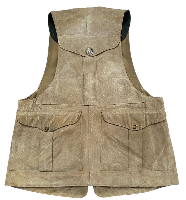 Peut inclure: Un gilet de couleur beige avec plusieurs poches et une fermeture &agrave; bouton. Le gilet a un col haut et un aspect vieilli, sugg&eacute;rant qu'il est fait d'un mat&eacute;riau durable. Il comporte deux grandes poches sur le devant et une plus petite sur la poitrine.
