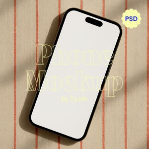 May include: A black smartphone mockup with a blank white screen, angled on a beige fabric with vertical orange stripes. The text "Phone Mockup by Lyuie" is overlaid on the screen. A yellow flower-shaped sticker with the text "PSD" is in the upper right corner.