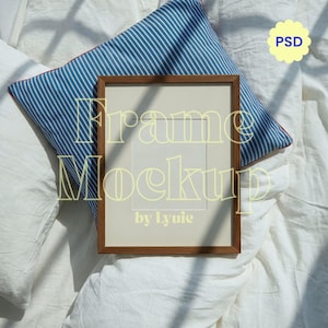 以下が含まれることがあります： ライトイエローのフォントで「Frame Mockup by Lyuie」というテキストが入った長方形の茶色の木製フレームモックアップ。 フレームは白い表面にあり、背景には青と白のストライプの枕があります。 「PSD」という単語は黄色の花の形をしています。