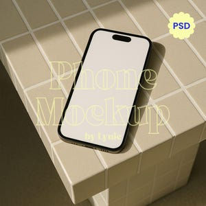 May include: A black smartphone mockup with a blank white screen rests on a beige tiled surface. The phone is angled, showcasing its sleek design. The words "Phone Mockup" are overlaid on the image, along with a "PSD" icon.