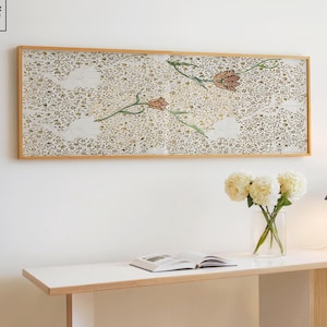 May include: A contemporary white desk with a light wood trim and white legs. A framed floral print hangs above the desk. A vase of white flowers, a lamp, and an open book are on the desk. The Stag & Print logo is in the upper left corner.