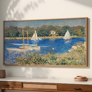 Op de afbeelding: Een ingelijst landschapsschilderij toont zeilboten op een blauw meer, met een klein huis en bomen op de achtergrond. Het kunstwerk zit in een houten lijst en hangt boven een houten console.
