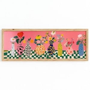 Puede incluir: Una impresión artística enmarcada que presenta una fila de jarrones coloridos, cada uno con un patrón único y lleno de flores. El fondo es rosa y la mesa tiene un patrón de cuadros verdes y blancos.