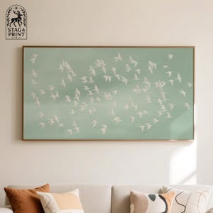 Peut inclure: Impression d'art encadrée rectangulaire représentant un vol d'oiseaux blancs sur un fond vert pâle. Le cadre est de couleur dorée. Le logo Stag & Print est en haut à gauche. Thème général : nature et vol.