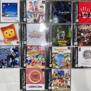 May include: A collection of PlayStation game cases, featuring various game titles with colorful cover art. The cases are in clear plastic, showcasing the game titles and artwork. Some titles include "Tear Ring Saga", "Wonder Trek", and "Harmful Park".