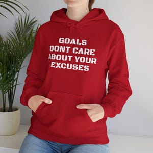 May include: Red hooded sweatshirt with the text "GOALS DONT CARE ABOUT YOUR EXCUSES" in white.