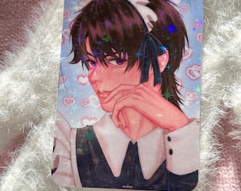May include: A rectangular holographic sticker featuring an anime-style illustration of a person in a maid outfit. The character has dark hair, purple eyes, and is wearing a white and black uniform. The background has a light blue and pink heart pattern.