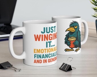 May include: Two white ceramic mugs. One mug has the text "JUST WINGING IT... EMOTIONALLY, FINANCIALLY, AND IN GENERAL" in orange, teal, and yellow. The other mug features a cartoon bird holding a coffee cup. The bird is teal with a yellow beak.