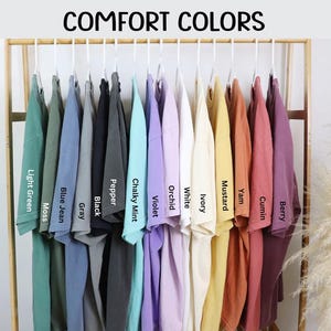 A clothing rack displaying a variety of colorful t-shirts, each with a different color label.