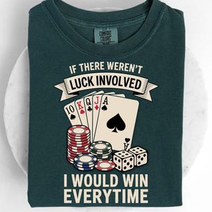Op de afbeelding: Donkergroen t-shirt met de tekst "IF THERE WEREN'T LUCK INVOLVED I WOULD WIN EVERYTIME." De afbeelding bevat speelkaarten, pokerchips en dobbelstenen. Het shirt is gemaakt van zacht materiaal.