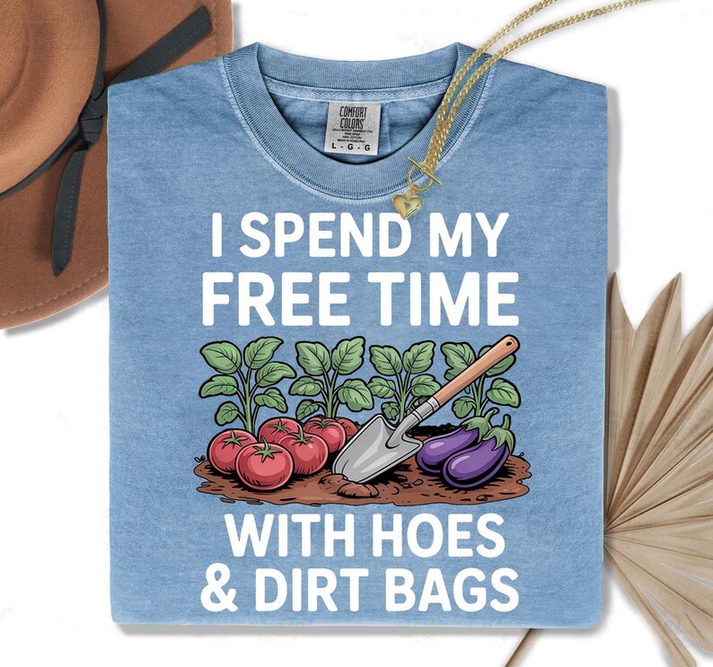 a blue t-shirt with a humorous text and an illustration of vegetables, including tomatoes and eggplants, along with a garden tool.