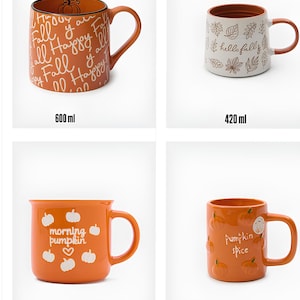 Può includere: Quattro tazze in ceramica con manico. In alto a sinistra: tazza arancione da 600 ml con testo 'Happy Fall' e zucca. In alto a destra: tazza bianca da 420 ml con motivi a foglie e testo 'hello fall'. In basso a sinistra: tazza arancione da 380 ml con zucche bianche e testo 'morning pumpkin'. In basso a destra: tazza arancione da 500 ml con illustrazioni di zucche e testo 'pumpkin spice'.