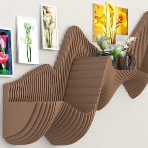May include: A brown, wave-shaped wall shelf with multiple levels and a unique design. The shelf is mounted on a white wall, with framed floral art and a vase of flowers. The shelf's dimensions are approximately 40 inches wide and 20 inches high.