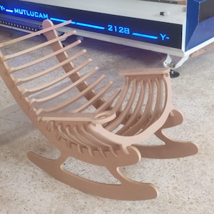 May include: A light brown wooden rocking chair with a curved back and seat. The chair has a slatted backrest and a curved seat. The chair is made of wood and has a natural finish. The chair is designed for comfort and relaxation.
