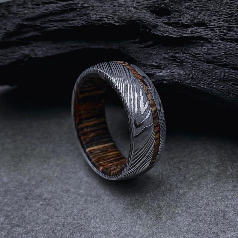 May include: A silver and brown patterned metal ring with a wood inlay.