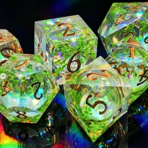 Puede incluir: Juego de seis dados poliédricos con exterior de resina transparente. Cada dado está relleno de follaje verde y números dorados. Diseñado para juegos de mesa.