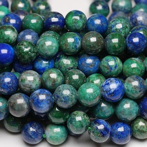 Peut inclure: Un brin de perles rondes de pierres précieuses vertes et bleues. Les perles sont un mélange de vert et de bleu, certaines ayant une couleur verte ou bleue plus prononcée. Les perles sont toutes lisses et polies.