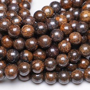 Peut inclure: Un brin de perles de pierres précieuses brunes et noires. Les perles sont rondes et ont une finition lisse et polie.