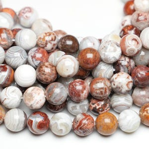 Peut inclure: Un brin de perles rondes en agate blanche avec des motifs marbrés bruns et rouges. Les perles mesurent environ 10 mm de diamètre.