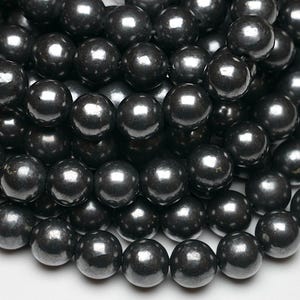 Peut inclure: Un collier de perles noires. Les perles sont rondes et ont une finition lisse et brillante.