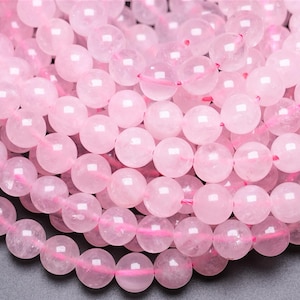Peut inclure: Gros plan sur un brin de perles de quartz rose. Les perles sont rondes et lisses, avec une apparence translucide.