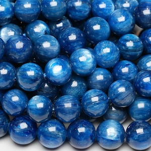 May include: A strand of round, blue gemstone beads. The beads have a striated, iridescent finish.