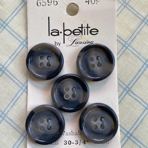 May include: Five dark gray buttons with four holes each, attached to a vintage card. The card reads "la petite by Lansing" and has the number "6596" and "30-3/4" printed on it. The buttons are round and have a marbled appearance.