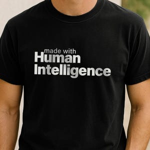 May include: A black t-shirt with the text "made with Human Intelligence" printed in white on the front.