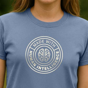May include: A blue t-shirt with a silver circle graphic that says "Made with Human Intelligence" and features a brain icon.