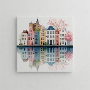 Könnte beinhalten: Aquarellmalerei mit farbenfrohen Gebäuden im europäischen Stil, die sich im Wasser spiegeln. Die Gebäude sind in Rosa, Blau, Gelb und Weiß gehalten, mit einem Kirchturm im Hintergrund. Kirschblüten in Rosa sind ebenfalls zu sehen.