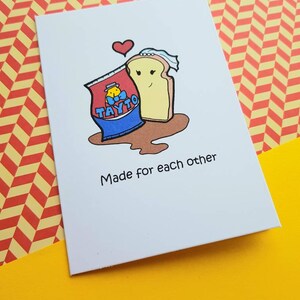 Peut inclure: Une carte blanche avec une illustration de dessin anim&eacute; d'un sac de chips Tayto et une tranche de pain avec un c&oelig;ur au-dessus. Le texte "Made for each other" est sous l'illustration.