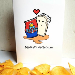 Peut inclure: Une carte de v&oelig;ux avec une illustration de dessin anim&eacute; d'un sac de chips Tayto et une tranche de pain avec un voile. Le texte sur la carte dit "Made for each other".