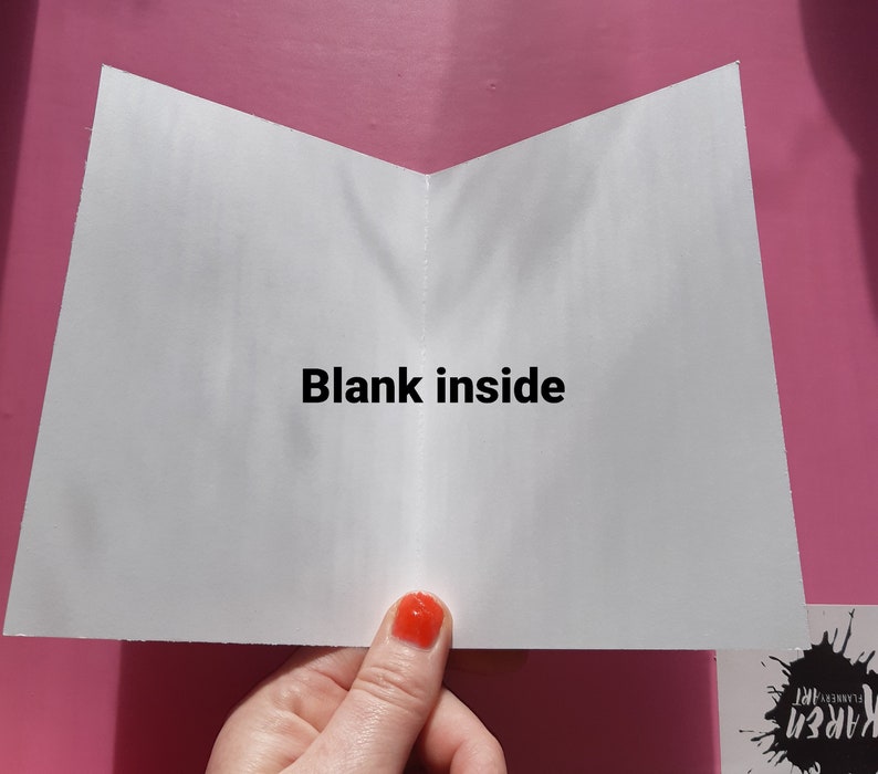 May include: A white card with the text "Blank inside" printed in black. The card is folded in half and is being held by a hand.