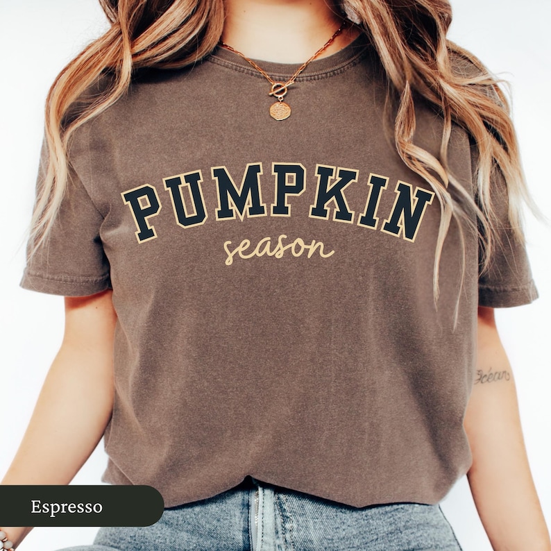 Pu&ograve; includere: T-shirt color espresso con le parole "PUMPKIN season" in un font in stile collegiale. La parte superiore presenta girocollo e maniche corte. La maglietta &egrave; in tinta unita e ha un aspetto vintage.