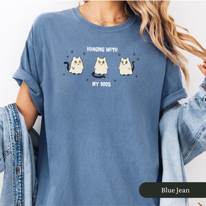May include: Blue jean-coloured t-shirt featuring the text "Hanging with my Boos" and three cartoon ghost cats. The cats have yellow eyes and black tails. The shirt has rolled-up sleeves.