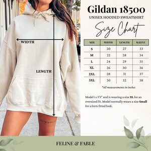 May include: A beige Gildan 18500 unisex hooded sweatshirt. The image includes a size chart with measurements in inches for sizes S to 3XL. The model is 5'5" and wearing an XL for an oversized fit. The brand name is Feline & Fable.